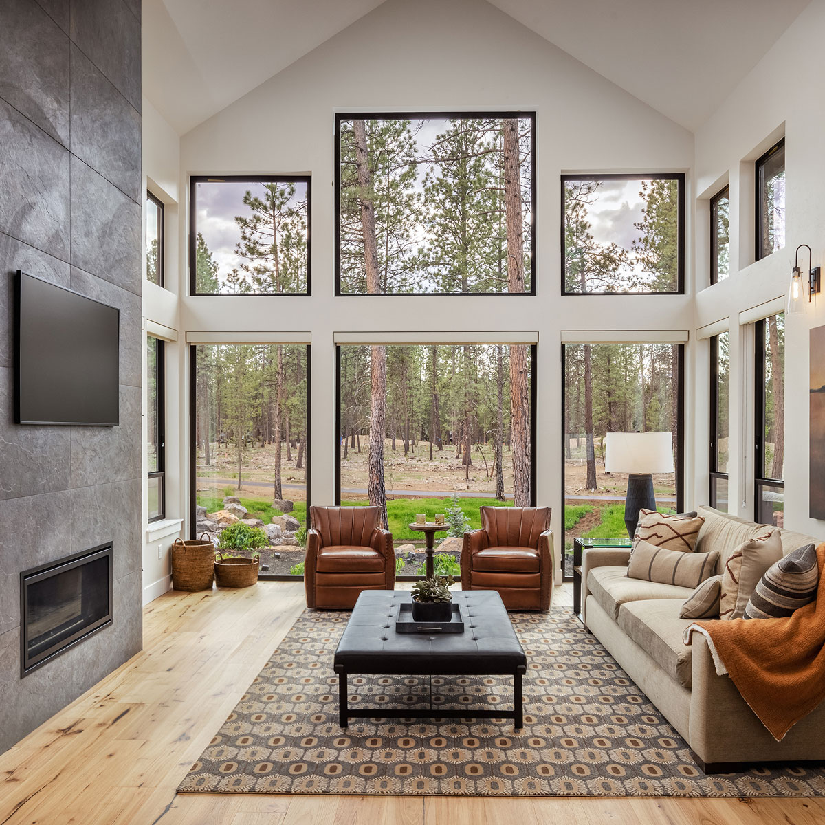 spacious living room with modern interior a stone fireplace and floor to ceiling windows